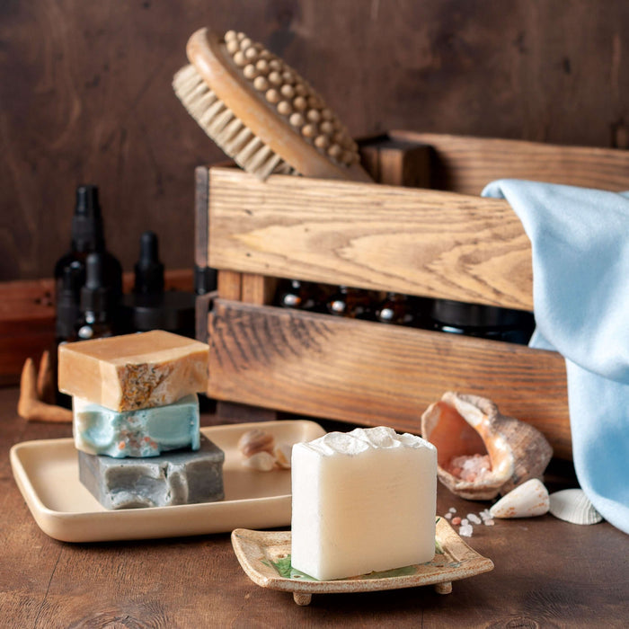 Stacked handmade soaps in a rustic still life. Includes wooden crate, amber bottles, and back brush. Alpaca Soaps AlpacaSoaps