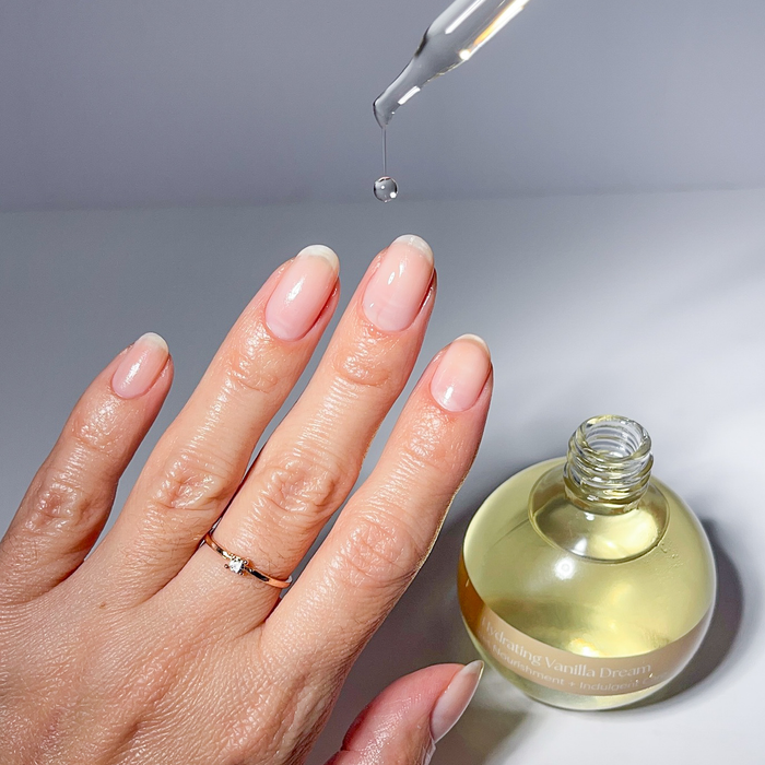 Applying Vanilla Dream cuticle oil with the dropper to a nude manicure