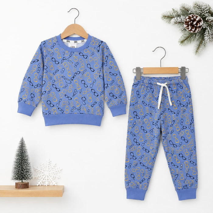 A children's two-piece sweatshirt and jogger pants set in a dusty blue color, decorated with a repeating pattern of gold and navy glasses. The sweatshirt is shown on a wooden hanger on the left, and the matching pants are shown on a metal hanger on the ri