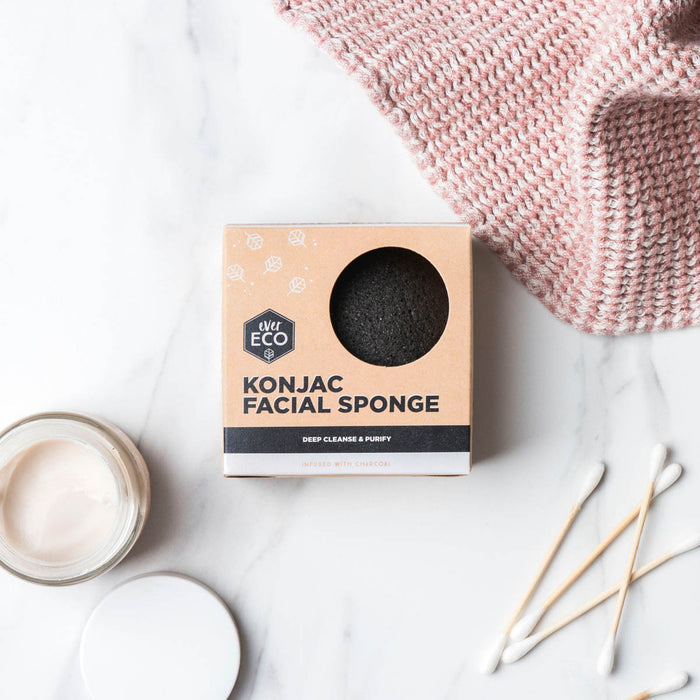 Charcoal konjac sponge in packaging on a marble surface with a pink cloth.
