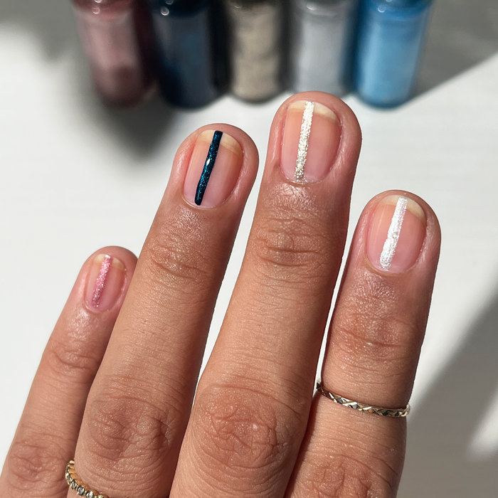 Metallic Era liner used for a thin navy stripe accent on a nude manicure with the bottles