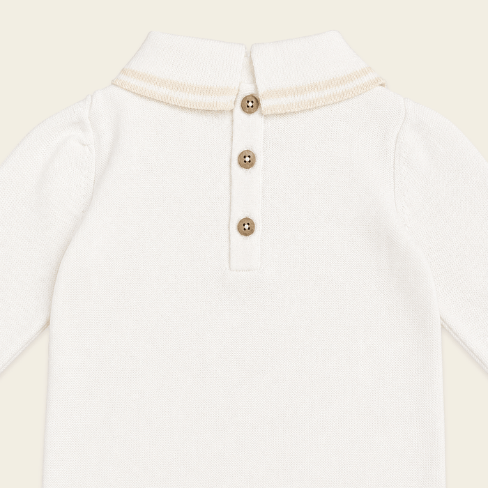 close up back view of milan dove white cable knit baby jumpsuit made of organic cotton