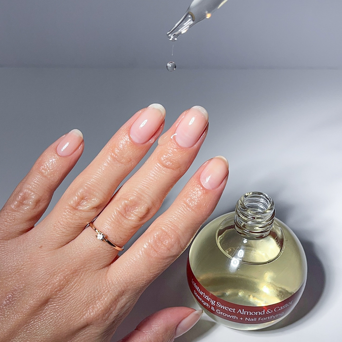 Applying Sweet Almond & Castor cuticle oil with the dropper to a nude manicure