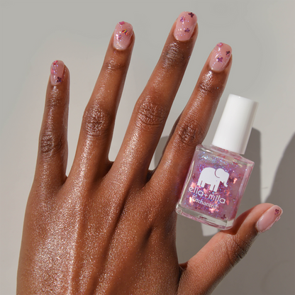 New Beginnings pink butterfly glitter nail polish on a medium skin tone with the bottle