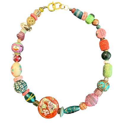 A handmade beaded necklace featuring a variety of colorful, patterned, and textured glass beads in orange, green, pink, blue, and yellow, with a gold clasp, shown on a plain white background.