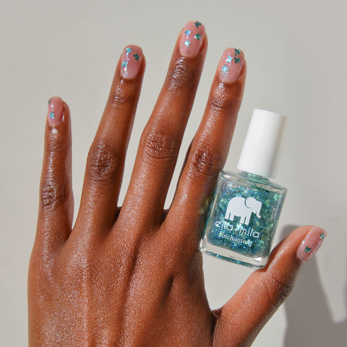 Rise and Fly teal butterfly glitter nail polish on a medium skin tone with the bottle