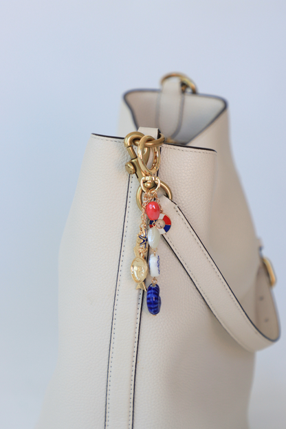 Beige handbag with a decorative charm on a light blue background