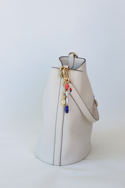 White handbag with colorful charms on a light gray background