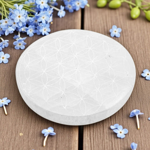 Round selenite charging plate on a wooden surface with blue flowers