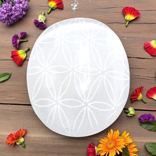 White Selenite plamstone with floral pattern on a wooden surface with colorful flowers.