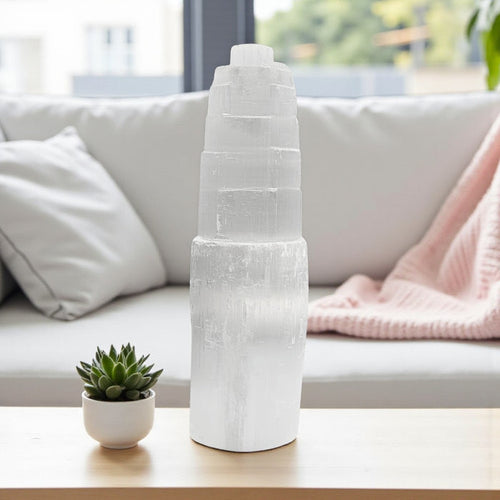White selenite lamp on a table with a potted plant and a couch in the background