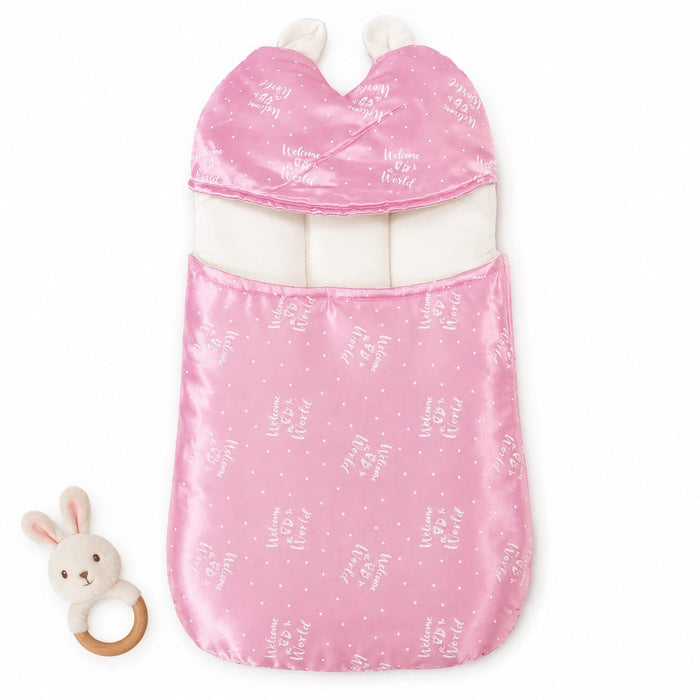 A pink baby sleep bag with white bunny and star patterns, featuring a soft white inner lining and two white bunny ears at the top. A small plush bunny teething ring toy is placed to the left on a clean white background.