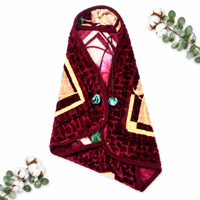 A plush fleece blanket with a geometric pattern, styled as a flat-lay on a white background with decorative cotton bolls and eucalyptus leaves. The blanket features a deep burgundy velvet exterior with a honeycomb texture, cream and yellow geometric panel