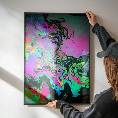 Abstract Oil Slick print with vibrant pink, green, and blue swirls in a black frame, held by hands.