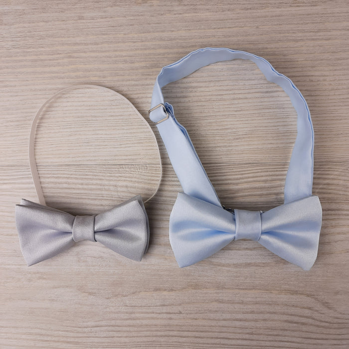Two pre-tied boys bow ties in ivory and light blue with adjustable neckstraps, perfect for formalwear and special occasions.