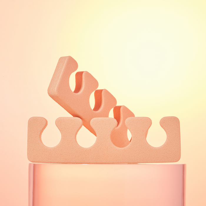 Two peach foam toe separators on a peach background