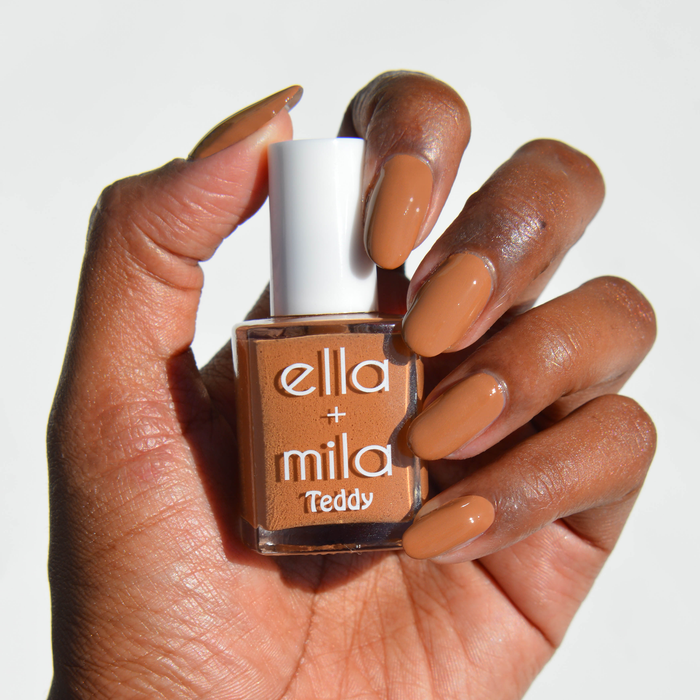 Teddy Collection caramel brown nail polish on a deep skin tone, hand holding the bottle