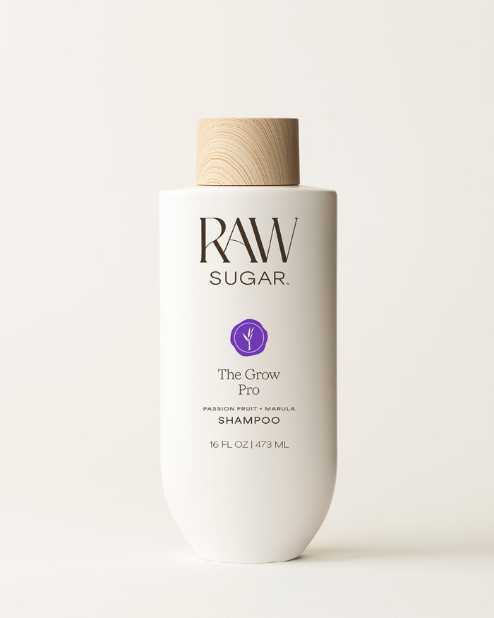 Bottle of Raw Sugar Grow Pro Shampoo on a cream background, designed to help strengthen hair with clean ingredients.
