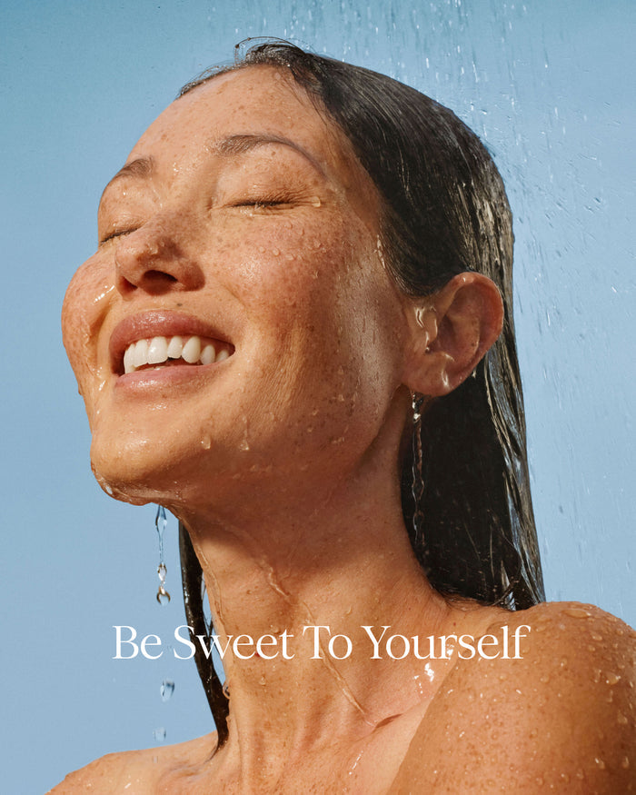 Woman under a shower with 'Be Sweet To Yourself' text