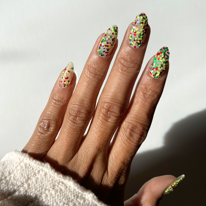 Tis the Season holiday confetti glitter over nude nails on a medium skin tone
