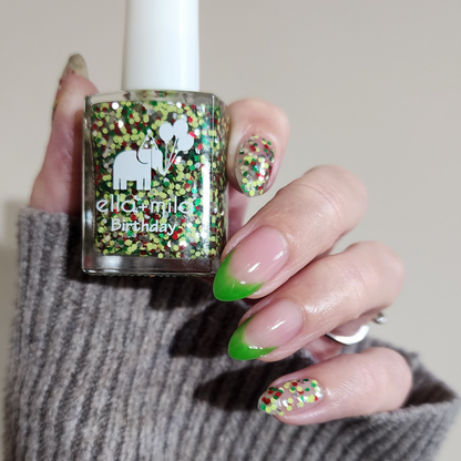 Tis the Season confetti glitter with a green French tip accent, holding the bottle