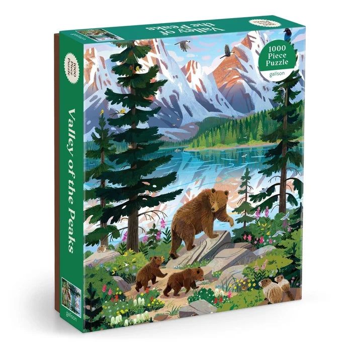 Enjoy assembling the "Valley of the Peaks | 1,000 Piece Jigsaw Puzzle" by Galison, featuring a breathtaking nature scene of a mountain landscape with a bear and three cubs strolling beside a tranquil lake, all framed by trees, birds, and snow-capped peaks. This captivating puzzle is perfect for wildlife and scenery enthusiasts alike.