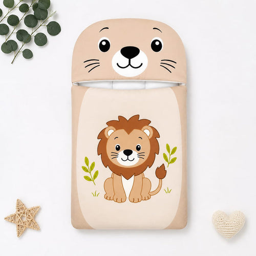 A children's sleep sack or blanket featuring a cute cartoon lion on the front and a matching lion-face hood, shown in a styled flat-lay with eucalyptus leaves, a star, and a small heart on a white background.