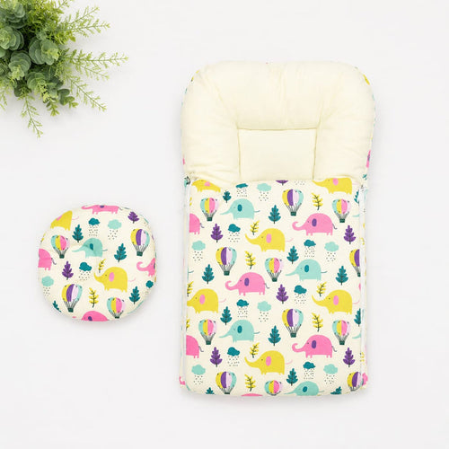 A baby travel seat cover and matching footmuff set with a colorful elephant and tree pattern on a cream background, displayed on a white surface with a green plant in the corner.