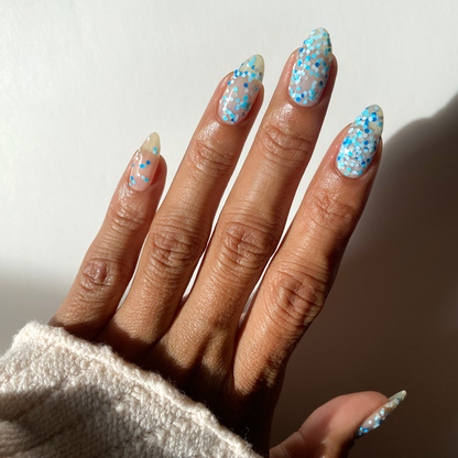 Winter Wishes blue and white confetti glitter nail polish on a medium skin tone