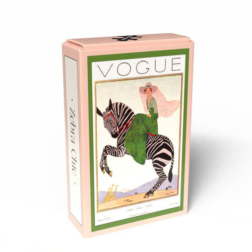 Zebra Chic | 99 Piece Jigsaw Puzzle by Penny Puzzle comes in a pink rectangular box with vintage Vogue art of a woman in green riding a zebra and “Zebra Chic” on the side, celebrating classic fashion magazine covers.